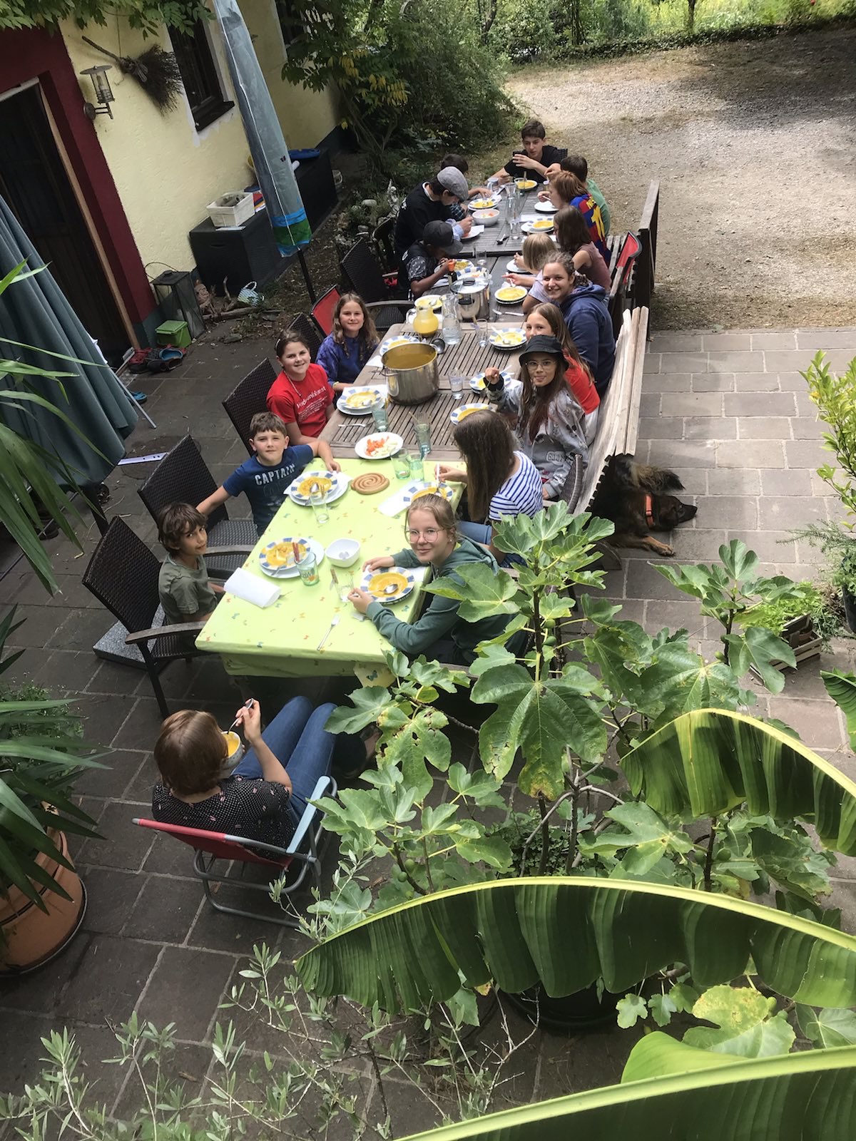 Kinder essen an einem langen Tisch im Freien